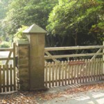 Elegant wooden gate and picket fence entrance with stone pillars, handcrafted by Richard Hope Wooden Gates, enhancing rustic charm for countryside cottages and private gardens.