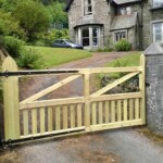 Handcrafted wooden gate for garden entrance with rustic stone pillars and decorative iron fittings, perfect for enhancing curb appeal and providing secure access.