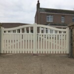 Elegant white wooden gates with decorative curved top, providing secure private access to residential property, crafted by Richard Hope Wooden Gates. Perfect for enhancing privacy and curb appeal.