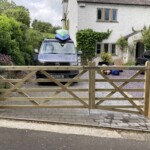 New wooden driveway gate installed in front of a residential property, crafted by Richard Hope Wooden Gates, showcasing durable timber construction and intricate design, enhancing curb appeal and security.