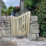 Elegant wooden garden gate with natural timber finish, custom-designed for privacy and style, surrounded by lush greenery and traditional stone walls. Perfect for enhancing outdoor aesthetics.